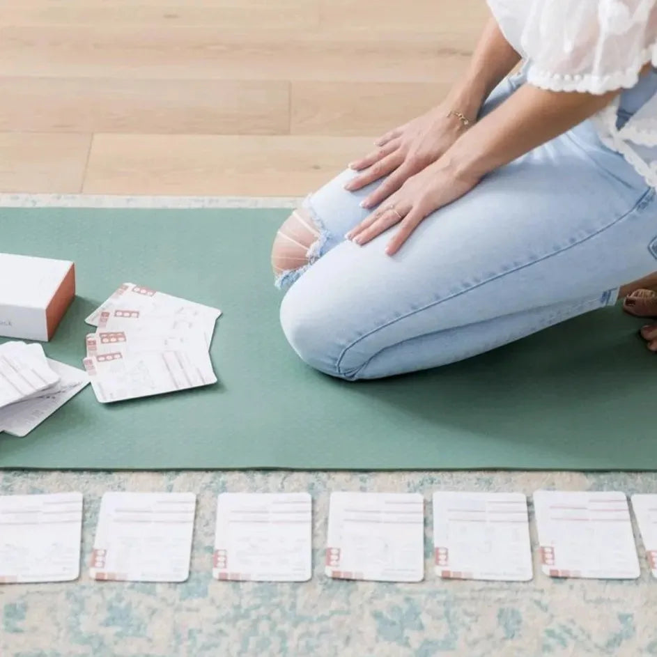 Yogi seated on yoga mat with yoga cards spread out in a sequence